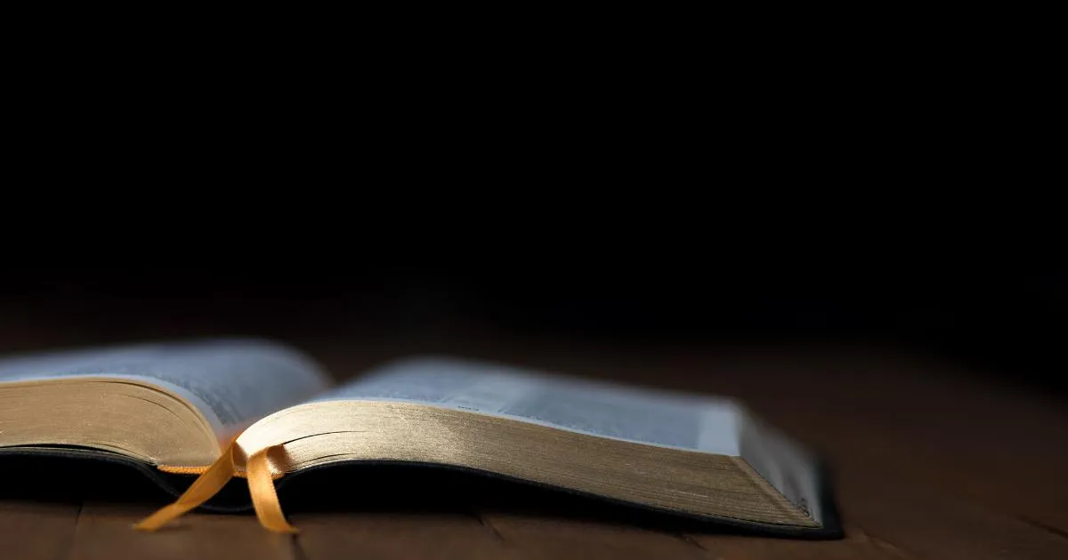 Oppslått bibel på et bord mot mørk bakgrunn